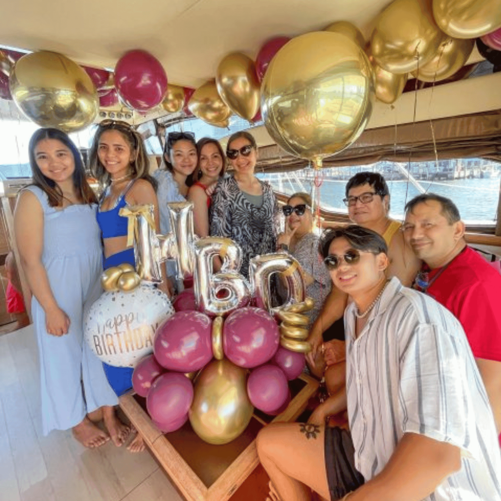 Birthday celebration group on yacht with gold balloons