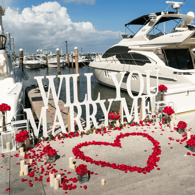 Cartaz 'Você quer casar comigo?' na marina com iate