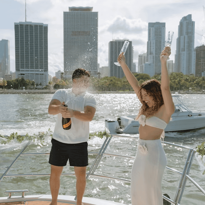 Casal celebrando o pedido com champanhe em iate